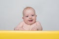 Cute smiling baby looking at the camera. Toddler sits at the table