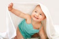 Cute smiling baby looking at camera under a white towel on a white background. portrait of a cute child Royalty Free Stock Photo