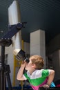 Cute smiling boy looking skyward through astronomical telescope. Child looking through tourist telescope, exploring landscape Royalty Free Stock Photo