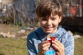 Cute smiling boy playing rubik`s cube on the backyard. Young kid solving rubik`s cube Royalty Free Stock Photo