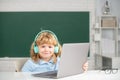 Cute smiling boy wearing headphones, study with laptop in classroom, listening audio lesson course. Elementary school Royalty Free Stock Photo