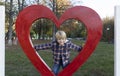 cute smiling boy 5-6 years old in a plaid shirt inside a big red heart looks happily at the camera Royalty Free Stock Photo