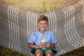 Cute smiling caucasian boy drinking water and having fun on hammock in backyard or outdoor. Kid swinging and relaxing in hammock Royalty Free Stock Photo