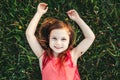 Cute smiling Caucasian girl resting in grass on meadow. Child lying on ground. Outdoors fun summer children activity. Kid having Royalty Free Stock Photo