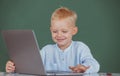 Cute smiling child using laptop computer, kid boy studying through online e-learning. Little funny programmer. Royalty Free Stock Photo