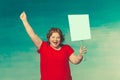 Cute smiling chubby red-haired woman screaming fervently, waving his hand in the second holds a protest poster on a blue