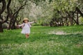 Cute smiling dressy baby girl on the walk in blooming cherry garden in spring Royalty Free Stock Photo