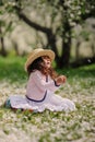 Cute smiling dressy baby girl on the walk in blooming cherry garden in spring Royalty Free Stock Photo