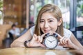 Cute smiling girl with alarm clock on wooden table
