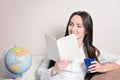 Cute smiling girl with a blue Cup and the diary, sitting on the couch in the room and reads. Royalty Free Stock Photo