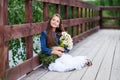 Cute smiling girl with a bouquet of daisies on the pier barefoot dreaming.