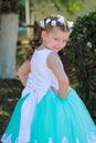 Cute smiling girl dressed in blue and white dress with a wreath of artificial flowers on her head, child in a festive dress on a n Royalty Free Stock Photo