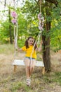 Cute smiling girl having fun on a swing in tree forest Royalty Free Stock Photo