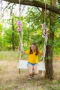 Cute smiling girl having fun on a swing in tree forest Royalty Free Stock Photo
