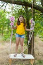 Cute smiling girl having fun on a swing in tree forest Royalty Free Stock Photo