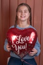 cute smiling girl holding red heart shaped balloon Royalty Free Stock Photo