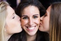 Cute smiling girl kissed on the cheeks by her friends.