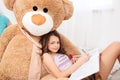 Cute smiling girl lying on big plush bear and drawing Royalty Free Stock Photo