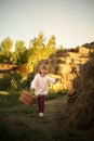 cute smiling girl runs rustic village with wicker basket  long blond hair  hayfield wheat hayloft harvesting feeding warm sunny Royalty Free Stock Photo