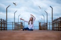 Cute smiling girl and seagulls, kid raised his hands up against the blue sky, sea, coast and flying seagulls. concept of tourism