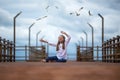 Cute smiling girl and seagulls, kid raised his hands up against the blue sky, sea, coast and flying seagulls. concept of tourism