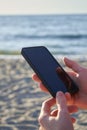 Cute smiling girl texting with her mobile phone message on a beach. Nice relax Royalty Free Stock Photo