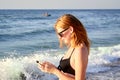 Cute smiling girl texting with her mobile phone message on a beach. Nice relax Royalty Free Stock Photo