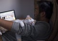 Cute smiling happy cat lying on the man`s shoulder while he is working on computer.