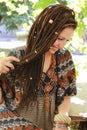Cute smiling hippie indie style woman with dreadlocks, dressed in boho style ornamental dress posing