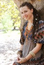 Cute smiling hippie indie style woman with dreadlocks, dressed in boho style ornamental dress posing outdoor Royalty Free Stock Photo
