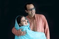 Cute smiling Indian girl in India traditional blue dress with her father standing on black background, daughter kid hugging her Royalty Free Stock Photo