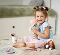 Cute smiling kid girl sits on soft carpet at home hugging playing with dolls and drawing pictures with colorful pencils Royalty Free Stock Photo