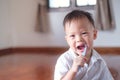 Cute smiling little Asian 30 months / 2 year old toddler boy child wearing pajama holding toothbrush and learn to brushing teeth i