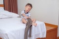 Cute smiling little Asian 2 years old toddler boy child sitting in bed concentrate on putting on his pants