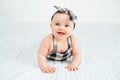 Cute smiling little baby girl sitting on bed. Seven month old infant child on grey soft blanket Royalty Free Stock Photo