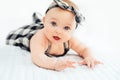 Cute smiling little baby girl sitting on bed. Seven month old infant child on grey soft blanket Royalty Free Stock Photo