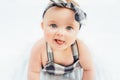 Cute smiling little baby girl sitting on bed. Seven month old infant child on grey soft blanket Royalty Free Stock Photo