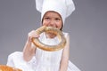 Cute and Smiling Little Caucasian Girl In Cook Uniform Posing With Doughnut Bread Roll Royalty Free Stock Photo