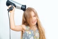 Little girl drying her long hair with hair dryer Royalty Free Stock Photo