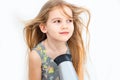 Little girl drying her long hair with hair dryer Royalty Free Stock Photo