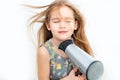 Little girl drying her long hair with hair dryer Royalty Free Stock Photo