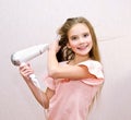 Cute smiling little girl child drying her long hair with hair dryer Royalty Free Stock Photo