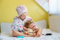 Cute smiling little girl child playing with her doll at home. Preschool child in bathrobe after taking bath brushing Royalty Free Stock Photo