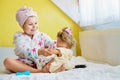 Cute smiling little girl child playing with her doll at home. Preschool child in bathrobe after taking bath brushing Royalty Free Stock Photo