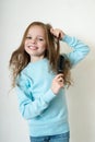 Cute smiling little girl combing her hair comb makes hair