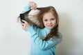 Cute smiling little girl combing her hair comb makes hair