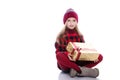 Cute smiling little girl with curly hairstyle wearing knitted sweater, scarf and hat holding christmas gift isolated on white Royalty Free Stock Photo