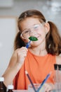 Cute smiling little girl doing science project, holding a leaf in tweezers Royalty Free Stock Photo