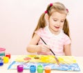 Cute smiling little girl drawing with paint and paintbrush Royalty Free Stock Photo