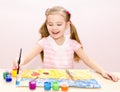 Cute smiling little girl drawing with paint and paintbrush Royalty Free Stock Photo